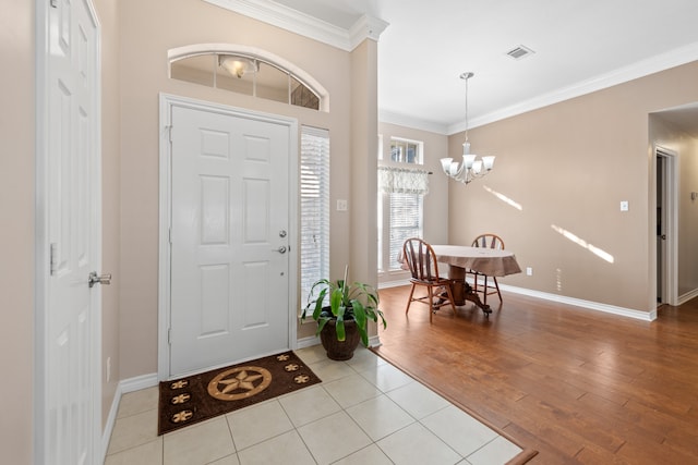 foyer with ornamental molding, a chandelier, and light hardwood / wood-style floors