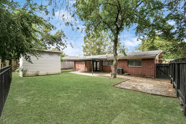 rear view of house with cooling unit, a patio area, and a yard