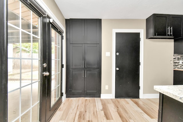 kitchen featuring light stone counters, light hardwood / wood-style floors, and tasteful backsplash