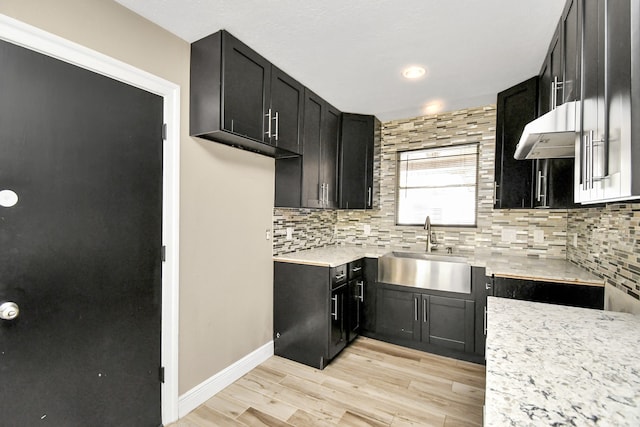 kitchen with light wood-type flooring, decorative backsplash, and sink