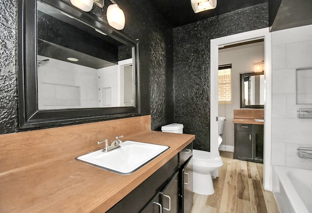 full bathroom featuring independent shower and bath, wood-type flooring, vanity, and toilet