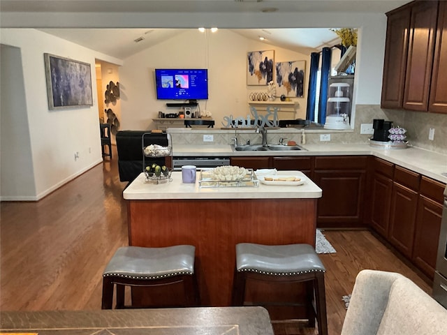 kitchen featuring a kitchen bar, backsplash, vaulted ceiling, sink, and a kitchen island