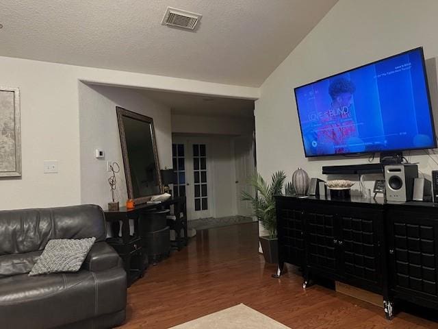 living room with lofted ceiling, wood-type flooring, and a textured ceiling