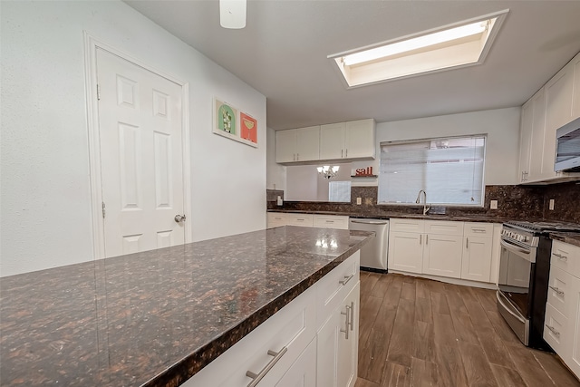 kitchen with white cabinetry, stainless steel appliances, dark wood-type flooring, dark stone countertops, and decorative backsplash