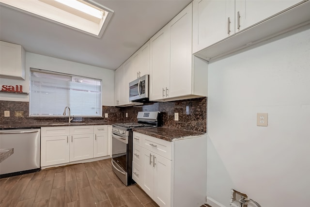 kitchen featuring appliances with stainless steel finishes, white cabinetry, sink, and wood-type flooring