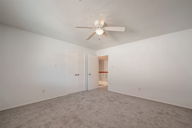 carpeted spare room featuring a textured ceiling and ceiling fan