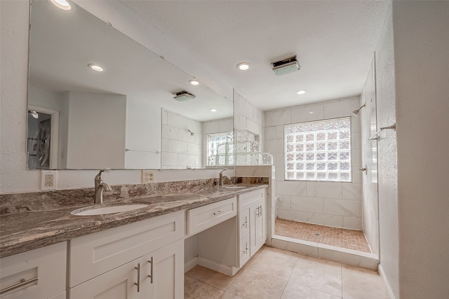 bathroom featuring vanity, a tile shower, a textured ceiling, and tile patterned flooring