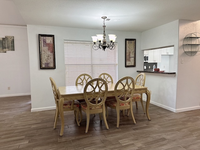 dining room with dark wood-type flooring, a textured ceiling, and a chandelier