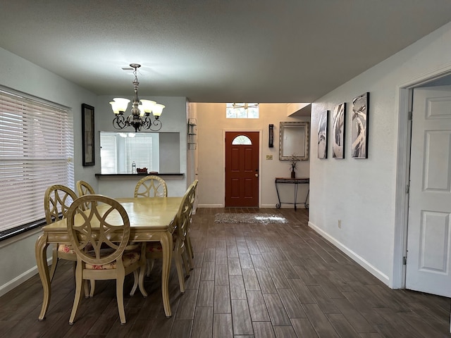 unfurnished dining area featuring a chandelier, a textured ceiling, and dark hardwood / wood-style flooring