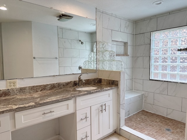 bathroom featuring vanity, a tile shower, a textured ceiling, and tile patterned floors