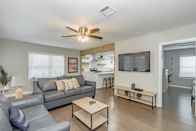 living room featuring ceiling fan, dark wood-type flooring, and a wealth of natural light