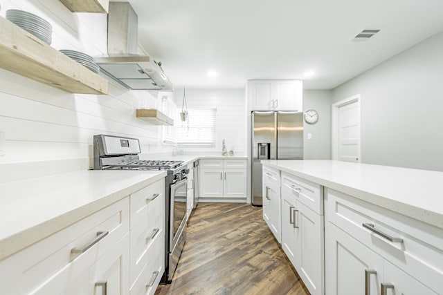 kitchen featuring dark wood-type flooring, white cabinetry, appliances with stainless steel finishes, decorative light fixtures, and extractor fan