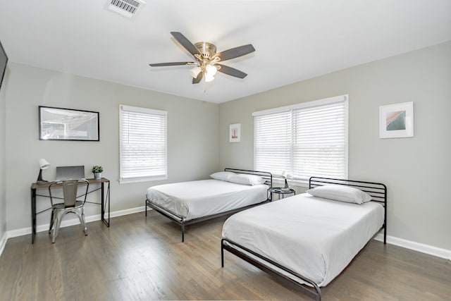 bedroom featuring ceiling fan, dark hardwood / wood-style floors, and multiple windows