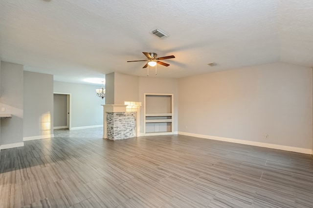 unfurnished living room with ceiling fan with notable chandelier, a textured ceiling, and hardwood / wood-style floors