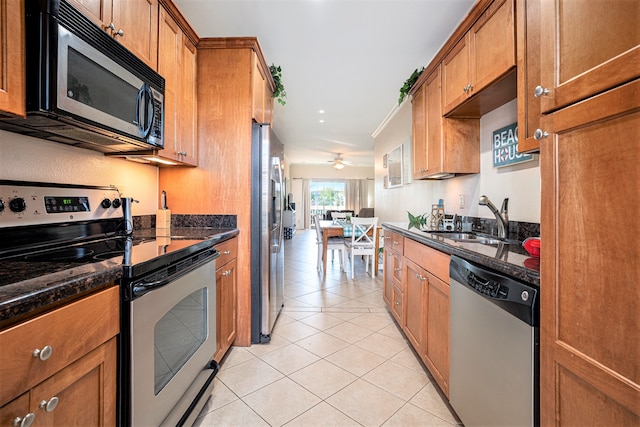 kitchen with ceiling fan, light tile patterned flooring, sink, stainless steel appliances, and dark stone counters