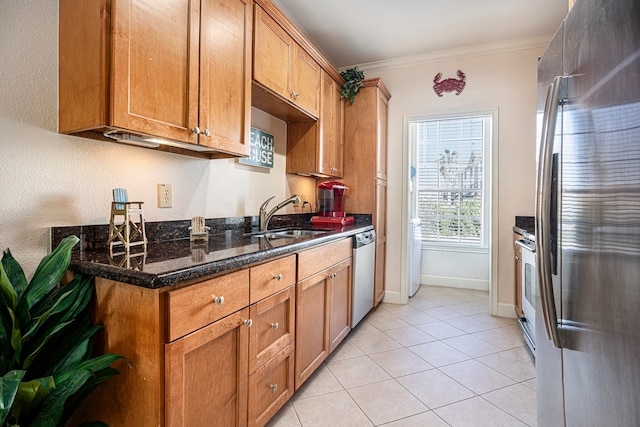 kitchen with dark stone counters, light tile patterned flooring, sink, stainless steel appliances, and ornamental molding