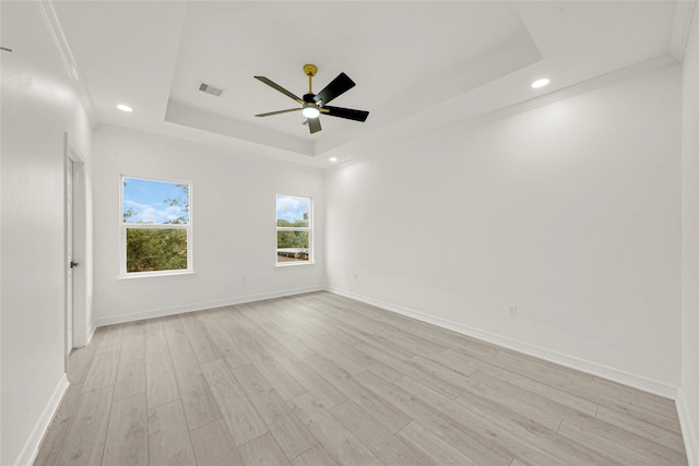 spare room with ceiling fan, ornamental molding, light wood-type flooring, and a tray ceiling