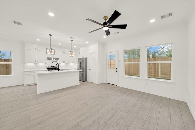 kitchen with stainless steel fridge, light hardwood / wood-style floors, an island with sink, white cabinets, and pendant lighting