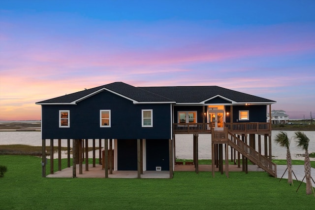 back house at dusk featuring a yard and a water view