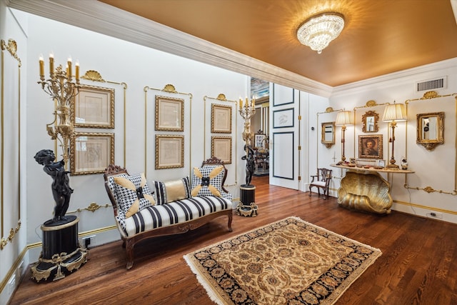 living area featuring a notable chandelier, ornamental molding, and hardwood / wood-style flooring