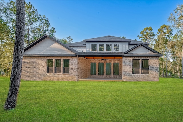 rear view of house with a lawn and a patio