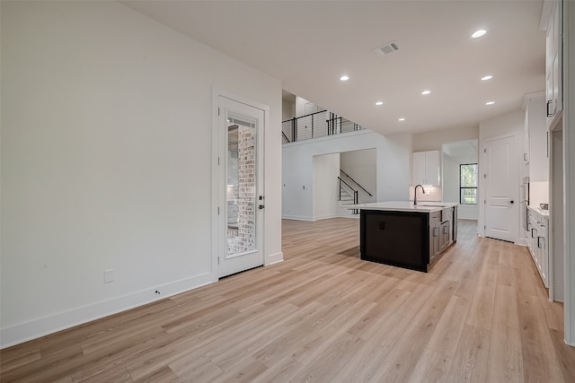 kitchen featuring an island with sink, white cabinetry, light hardwood / wood-style floors, and sink