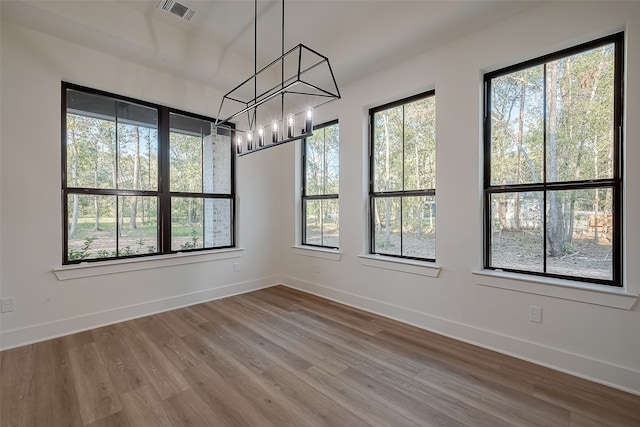 spare room with wood-type flooring and an inviting chandelier