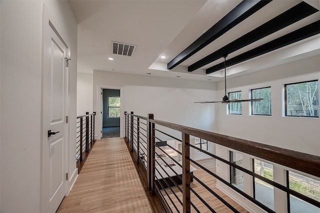 corridor with light wood-type flooring and beam ceiling