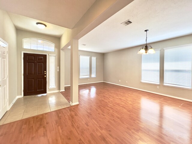 foyer entrance with light wood-type flooring and a chandelier