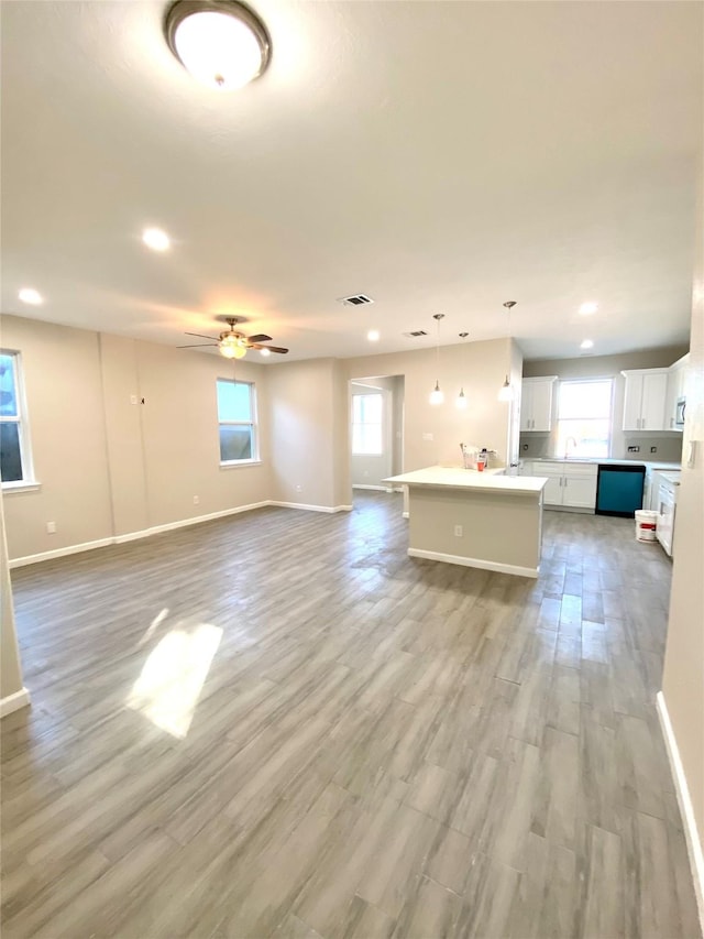 unfurnished living room featuring ceiling fan, light wood-type flooring, and sink