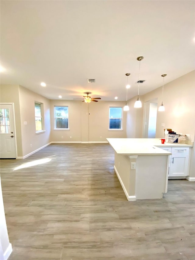 kitchen with ceiling fan, white cabinets, pendant lighting, and light wood-type flooring