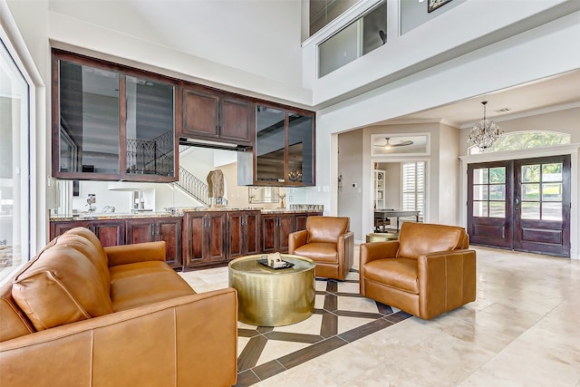 living room featuring light tile patterned floors, french doors, a high ceiling, crown molding, and an inviting chandelier