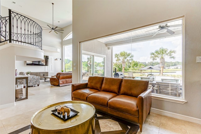 living room with ceiling fan, a towering ceiling, and light tile patterned floors