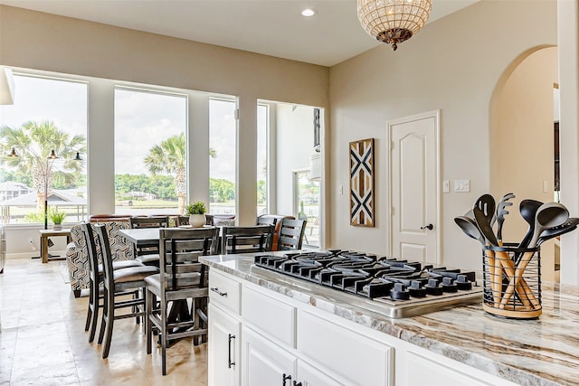 kitchen featuring stainless steel gas cooktop, white cabinetry, and light stone countertops