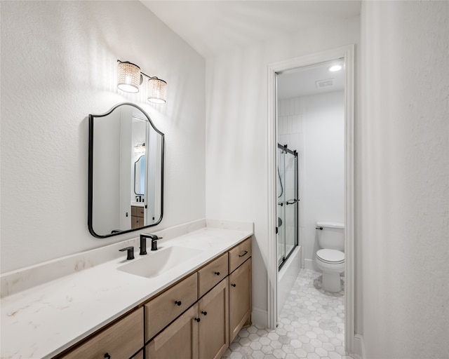 full bathroom with tile patterned flooring, vanity, combined bath / shower with glass door, and toilet