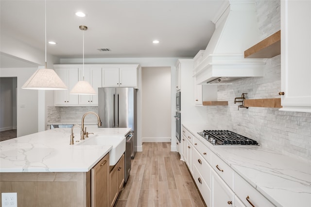 kitchen featuring a center island with sink, decorative light fixtures, and white cabinetry