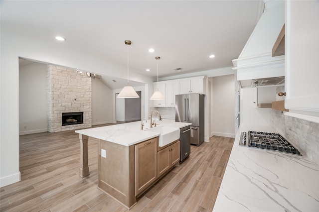 kitchen featuring pendant lighting, a center island with sink, white cabinets, sink, and stainless steel appliances