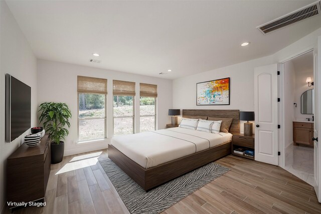 bedroom with ensuite bath and light hardwood / wood-style flooring