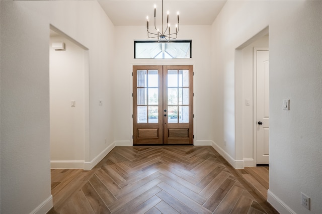 foyer entrance featuring french doors, light parquet flooring, and a notable chandelier