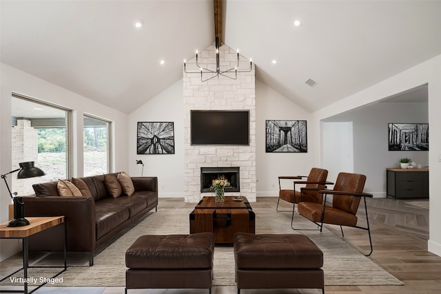 living room featuring beam ceiling, an inviting chandelier, high vaulted ceiling, a fireplace, and light hardwood / wood-style floors