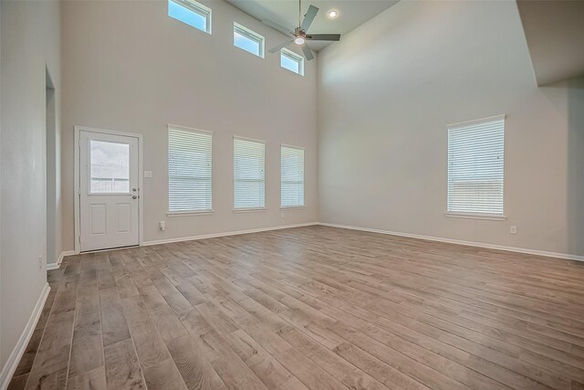 3423 Hackberry Tree Ln, Katy, TX 77449 - unfurnished living room featuring a towering ceiling, ceiling fan, wood finished floors, and baseboards