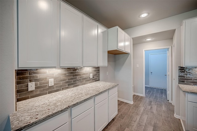 3423 Hackberry Tree Ln, Katy, TX 77449 - kitchen featuring decorative backsplash, light wood-style flooring, white cabinets, light stone counters, and baseboards