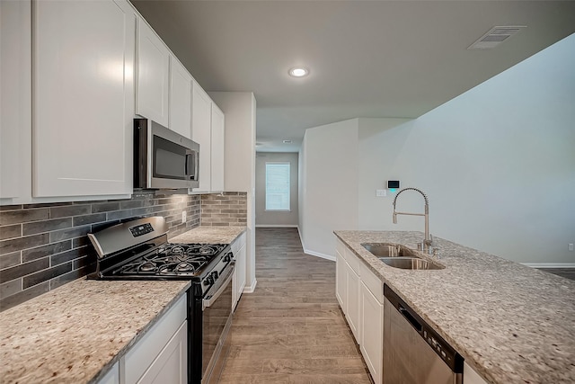3423 Hackberry Tree Ln, Katy, TX 77449 - kitchen featuring stainless steel appliances, a sink, light wood-type flooring, light stone countertops, and recessed lighting