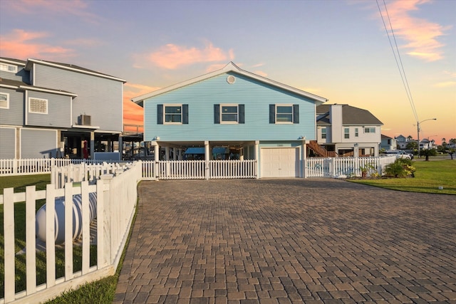 back house at dusk featuring a garage and a yard