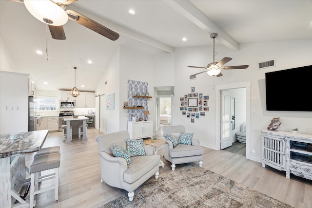 living room with ceiling fan, light hardwood / wood-style flooring, beam ceiling, and high vaulted ceiling