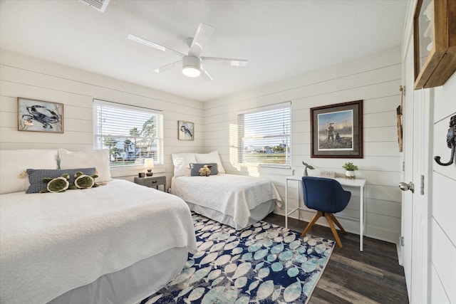 bedroom featuring dark wood-type flooring, wooden walls, multiple windows, and ceiling fan