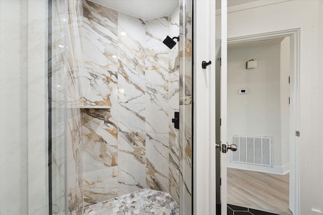 bathroom featuring hardwood / wood-style flooring and tiled shower