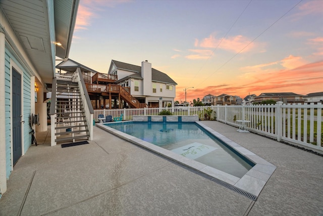 pool at dusk featuring a wooden deck and a patio area