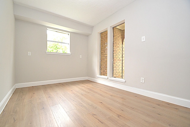 empty room featuring light wood-type flooring and a textured ceiling