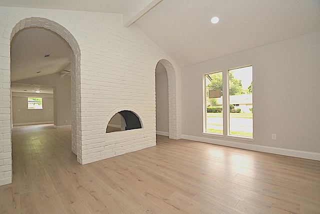 unfurnished living room featuring a fireplace, lofted ceiling with beams, light hardwood / wood-style floors, and a healthy amount of sunlight